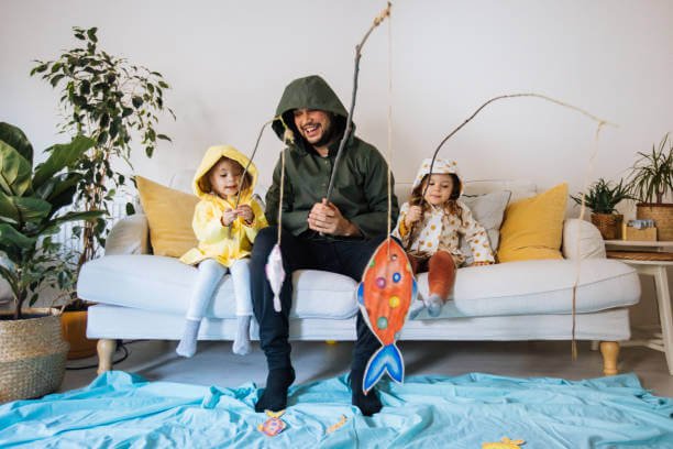 Jocuri terapeutice de jucat cu copiii in casa-Barbat cu undite de jucarie si doi copii pe canapea