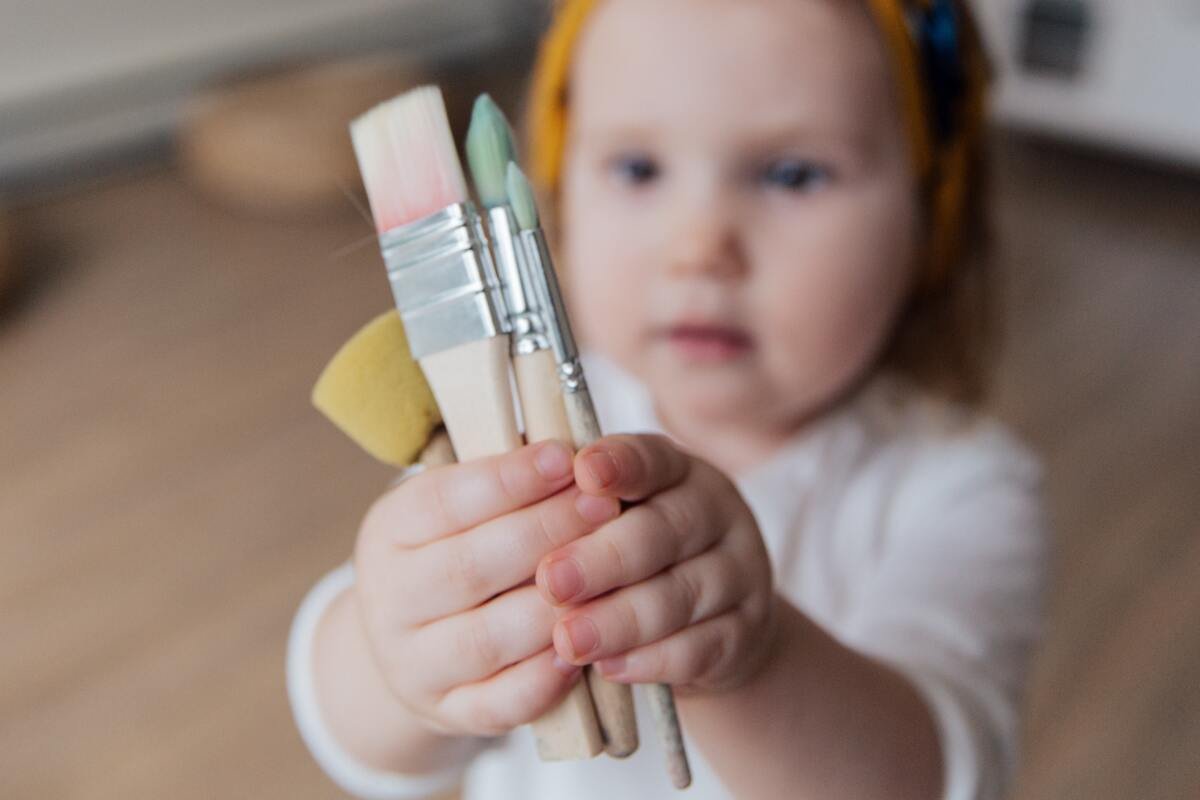 Jucariile in viata copiilor – stimularea creativitatii - o fetita ce tine pensule in mana
