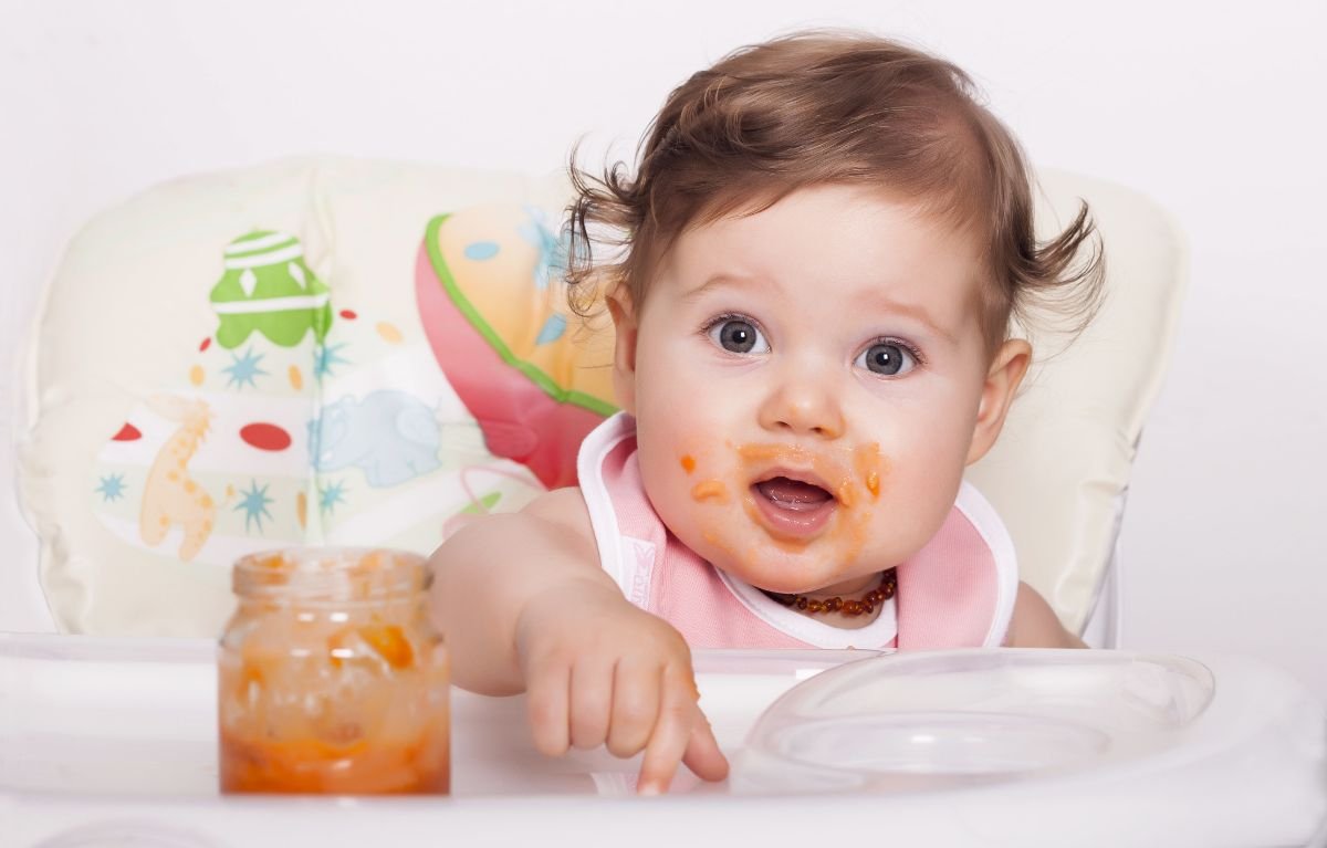 dezvoltare bebe 9 luni - bebelus, scaun luat masa, borcanel cu piure de morcovi