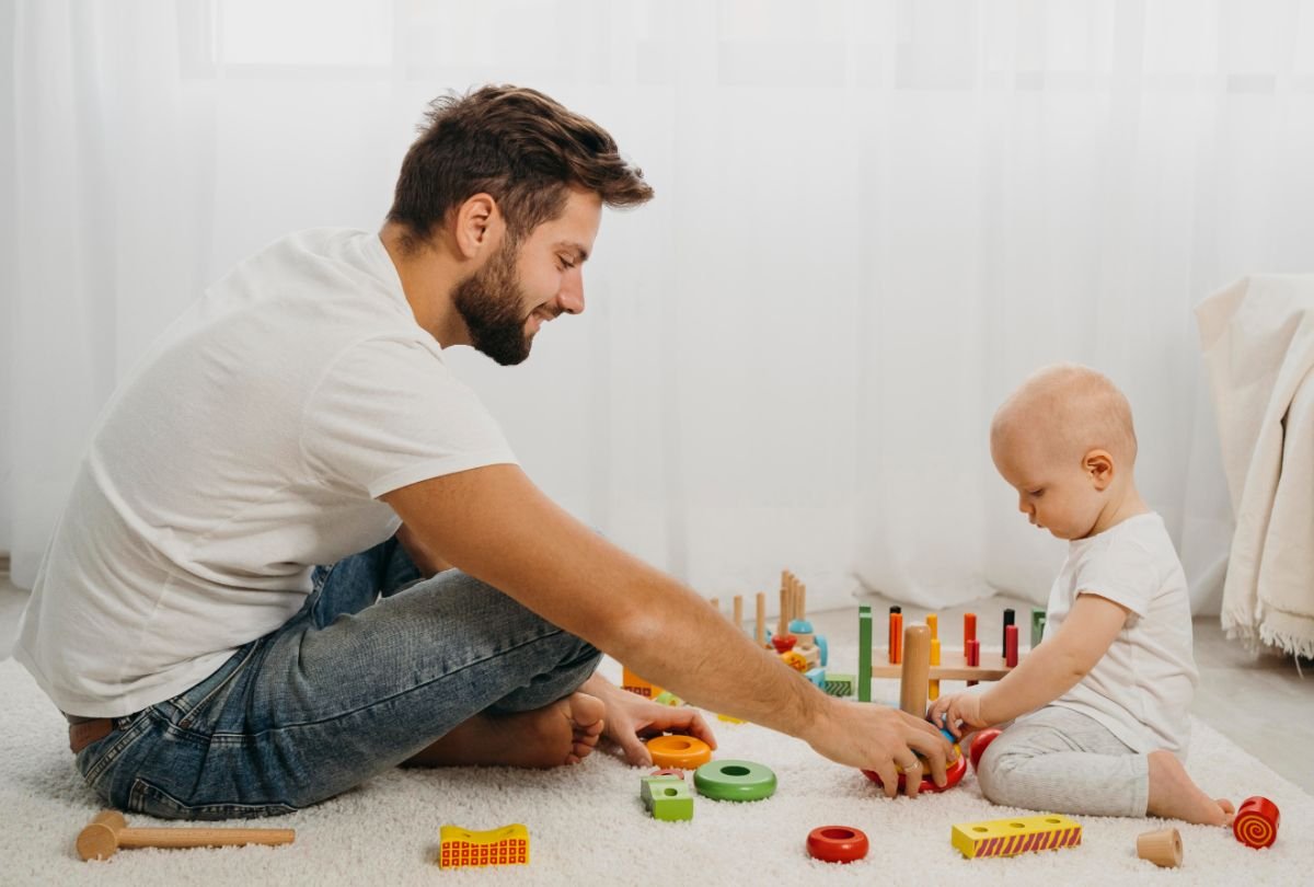 Dezvoltarea psihomotorie a copilului - copil mic, jucarii, tatal care ii explica, fundal alb