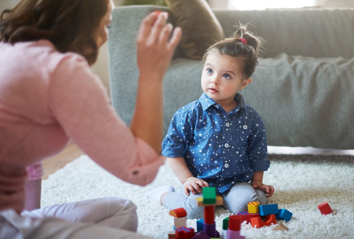 Dezvoltarea psihomotorie a copilului - fetita atenta la explicatiile mamei, canapea gri pe fundal
